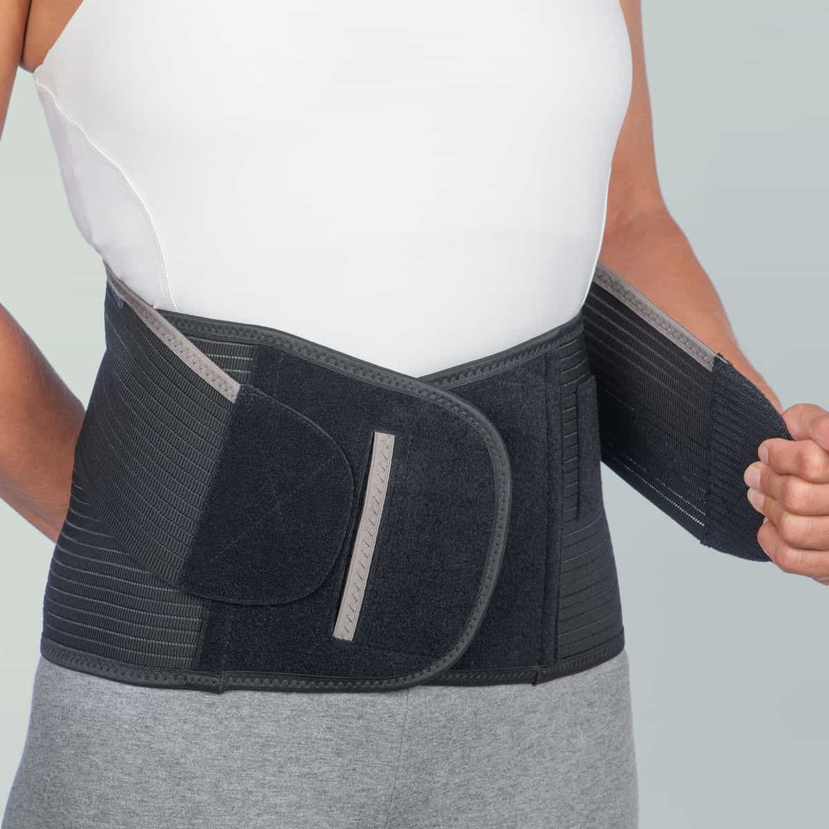 Future maman souriante utilisant la ceinture de soutien lombaire Maternella pour soulager son dos.